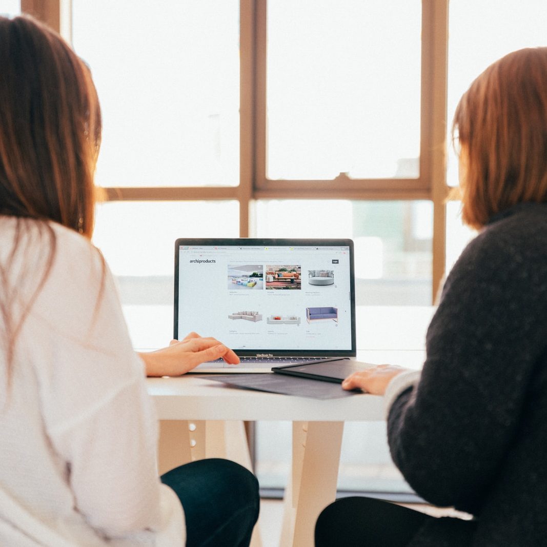 two women talking while looking at laptop computer